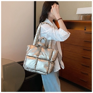 Silver quilted down cotton puffer tote bag shown on model with shoulder strap