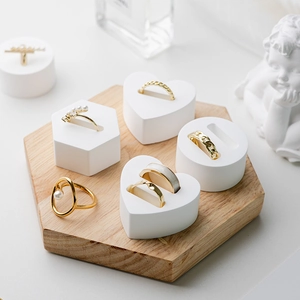 White geometric plaster ring display stand with a hexagonal wooden base for jewelry storage