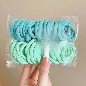 Detail of high-elasticity hair ties in sky blue and mint green within a clear bag