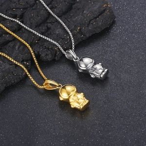 Detailed view of hip hop astronaut pendants in gold and silver finish on rock surface