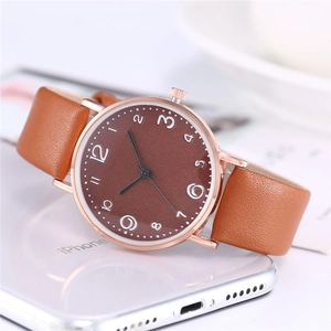 Brown leather strap watch with rose gold case resting on a white smartphone