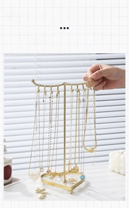 Detail of golden heart-based metal jewelry stand featuring necklace hooks and ring display