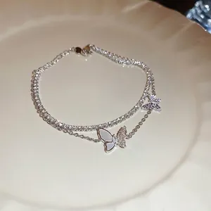 Double-layered butterfly zircon bracelet in silver finish on a cream decorative plate