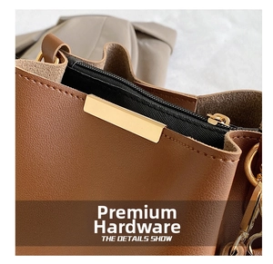 Close-up of premium gold hardware, black zipper, and brown leather detail on the bag