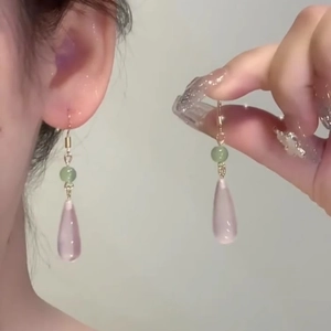 Detailed view of handmade teardrop earrings with green beads and pink resin drop charms