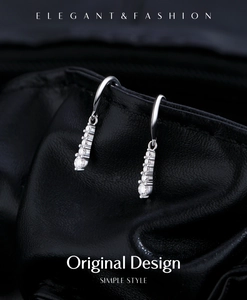 Detail view of shimmering D color moissanite drop earrings on textured black leather