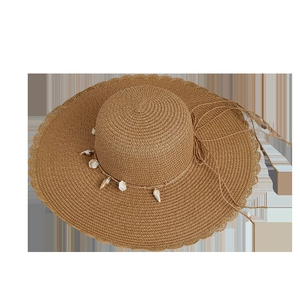 Handwoven straw beach hat with wide wavy brim and shell decoration on top view