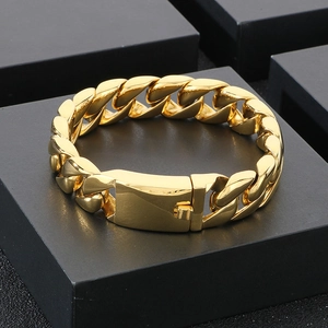 Close-up of polished gold plated Cuban link bracelet with clasp on textured stand