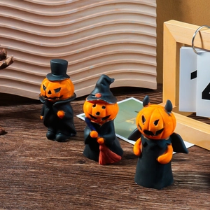 Three Halloween pumpkin figurines with hats and wings on a dark wood grain table