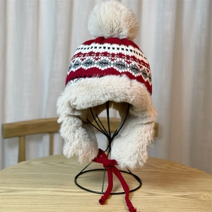 Detail of winter trapper hat with red geometric knit and thick faux fur lining