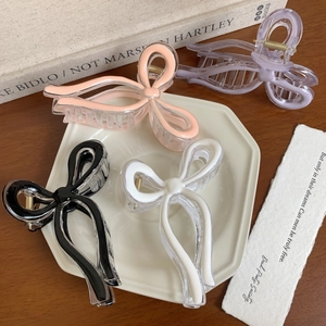 Elegant bow hair claw clips in four pastel colors on decorative ceramic tray display