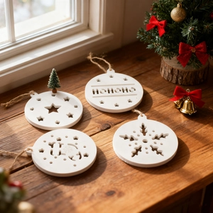 Set of four white Christmas ornaments with stars and HO HO HO cutouts on wooden background