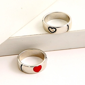Close-up of minimalist couple heart rings in silver with red and black enamel detail