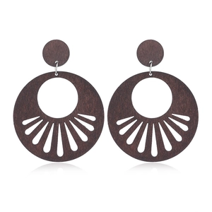 Detailed view of dark brown hollowed-out wooden round earrings with geometric patterns