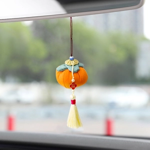 Handcrafted fabric persimmon Christmas ornament with yellow tassel hanging in car