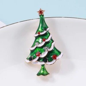 Detail of Christmas tree brooch with green enamel and rhinestones on a white plate