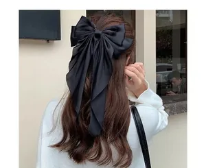 Detailed view of the large black satin bow hair clip with elegant long flowing ribbons