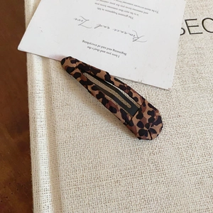 Dettaglio di fermaglio BB con stampa leopardata su tessuto neutro in stile vintage