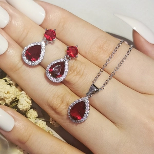 Detailed view of silver jewelry set with red pear-shaped stones and zircons worn on hand