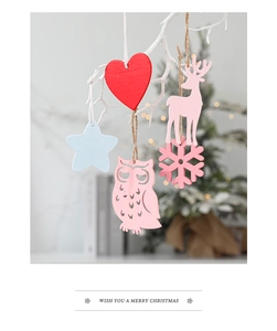 Close-up of wooden Christmas ornaments hanging on white branches with festive lights background