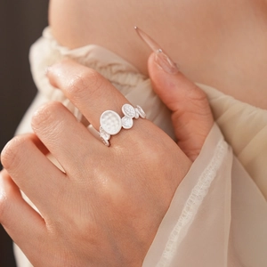Detail shot of a silver oval bubble ring with textured surface on a model's finger