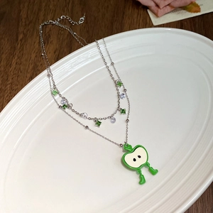 Vue détaillée du collier double rang en argent avec pendentif pomme verte sur assiette