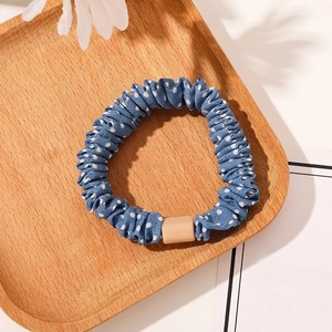 Close-up of blue polka dot scrunchie with rectangular buckle detail on a wooden tray