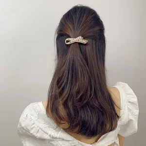 Detail of elegant bow hair clip featuring white pearls and rhinestones on a gold alloy base