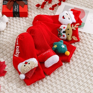 Christmas baby socks with red 3D reindeer and Santa decor on knitted blanket