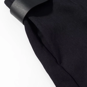 Detailed macro view of black textured twill fabric with leather belt and pocket stitching