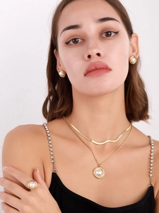 Close-up of golden mesh necklace, pearl earrings and ring set worn by a model