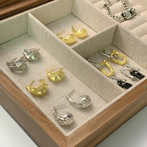 Detail shot of a wooden jewelry box with linen lining showcasing textured gold earrings