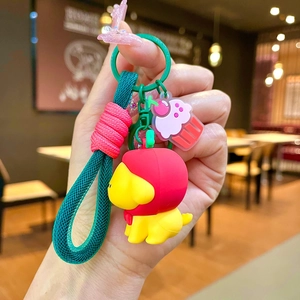 Detail of yellow puppy keychain with green woven rope and pink cake charm pendant