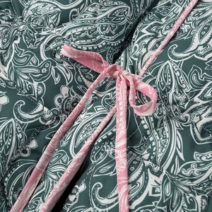 Detail of dark green paisley quilted fabric with a contrasting pink decorative bow tie