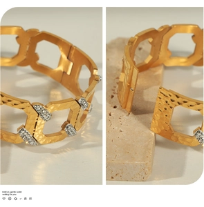 Detail of gold-plated geometric hammered bangle with cutout pattern and inlaid zircons