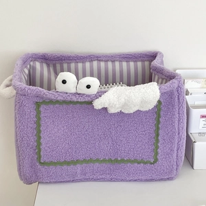 Close-up of purple plush monster storage basket with green wave trim and cute eyes