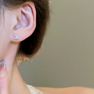 Detail view of flower stud earring with three zircon petals on golden setting