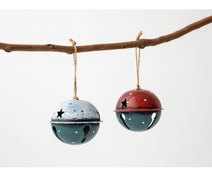 Macro shot of Nordic vintage metal Christmas bells with star cutouts on rustic wood branch