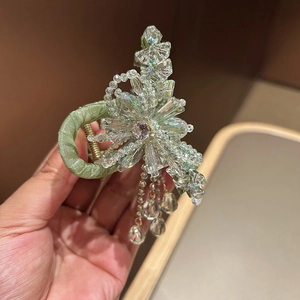 Detail of light green satin hair claw clip with sparkling crystal flowers and hanging tassels