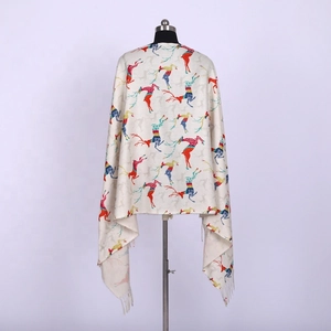 Detail of beige cashmere-like scarf featuring colorful reindeer patterns and tassel fringe