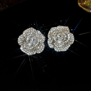 Macro shot of silver rose earrings with sparkling pavé diamonds on a black background