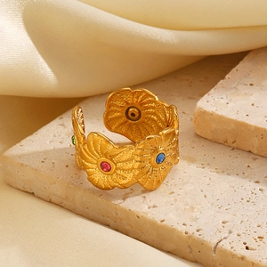 Golden sunflower open ring with colorful gemstones on a beige stone and silk background