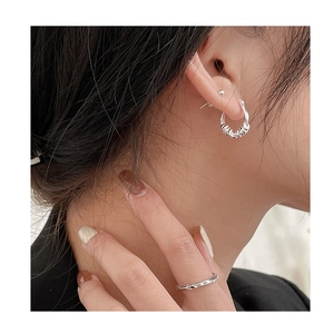 Close-up of S925 sterling silver hoop earrings and engraved ring on model