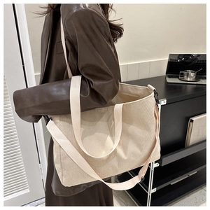 Close-up of beige corduroy tote bag showing striped texture and detachable shoulder strap