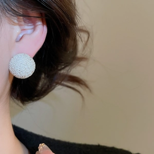 Close-up of large round silver stud earrings with frosted texture worn by a model