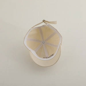 Close-up of beige baseball cap interior stitching and adjustable metal buckle strap
