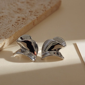 Detailed view of silver minimalist earrings featuring abstract wave and spiral metal design