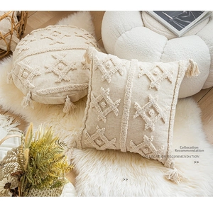 Detailed view of bohemian tufted cushion covers with tassels on a soft white rug