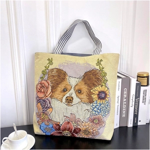Detail of floral embroidery and Papillon dog pattern on canvas tote bag with striped handle