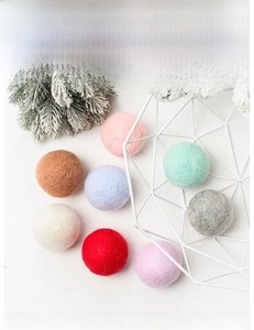 Close-up of colorful wool felt ball ornaments in a white wire basket for Christmas DIY